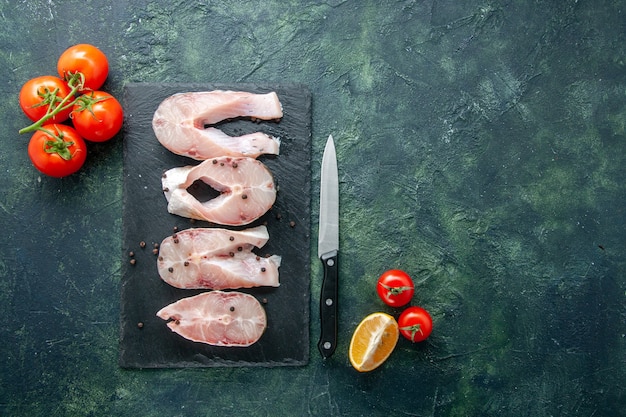 Vista de cima fatias de peixe fresco com tomates vermelhos em fundo escuro Carne do oceano Frutos do mar Refeição do mar Água Comida Pimenta Prato