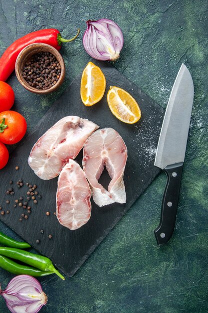 Vista de cima fatias de peixe fresco com tomates vermelhos em uma mesa azul escuro carne do oceano refeição de frutos do mar comida pimenta prato de água mar