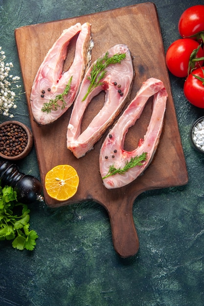 vista de cima fatias de peixe fresco com verduras e tomates em fundo escuro