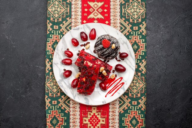 Vista de cima fatias de torrão vermelho com bolo de chocolate em fundo cinza bolo de torta de nougat biscoito de frutas doces