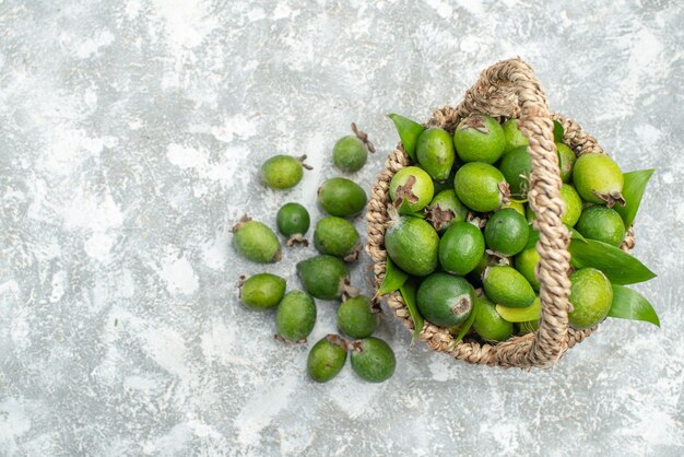 Vista de cima feijoas frescas em uma cesta de vime em um espaço livre de superfície cinza