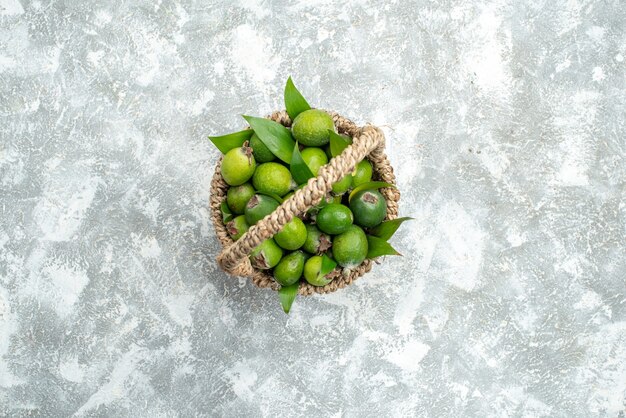Vista de cima feijoas frescas em uma cesta de vime em um espaço livre de superfície cinza