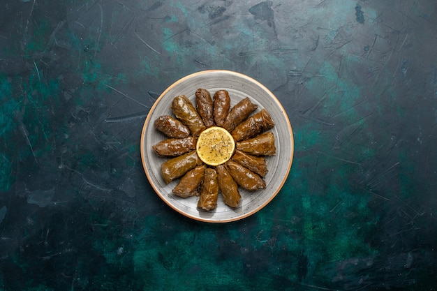 Foto grátis vista de cima folha dolma deliciosa refeição de carne oriental enrolada dentro de folhas verdes na mesa azul escuro refeição de carne comida jantar vegetais saúde caloria