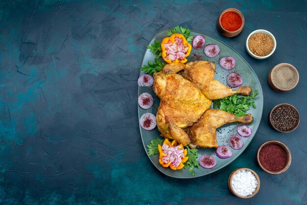 Vista de cima frango cozido com cebola e verduras dentro do prato na mesa azul escura frango assar carne no forno