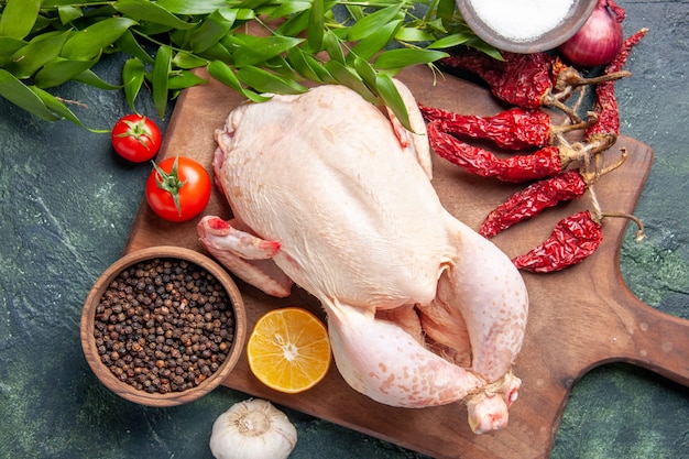 Vista de cima frango cru fresco com tomates vermelhos em fundo azul escuro cozinha refeição foto animal comida carne cor fazenda