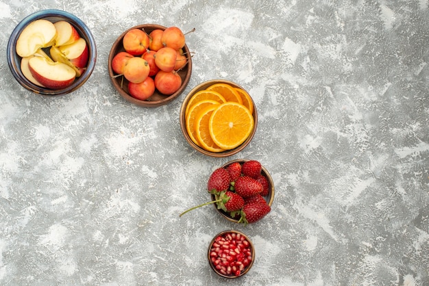 Vista de cima frutas fatiadas, maçãs e laranjas com bagas em fundo claro frutas frescas vitaminas saudáveis