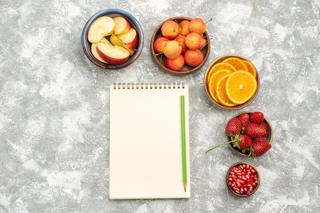 Vista de cima frutas fatiadas, maçãs e laranjas com bagas no fundo branco frutas frescas vitaminas maduras saúde