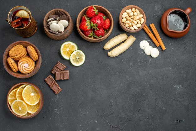 Vista de cima, frutas frescas, morangos e limões com biscoitos na superfície cinza