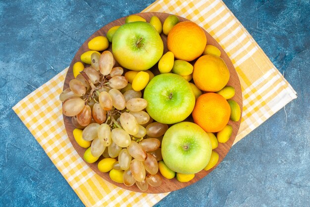 Vista de cima frutas frescas tangerinas, maçãs e uvas na mesa azul