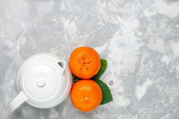 Vista de cima laranjas frescas com chaleira no fundo branco claro frutas cítricas frescas exóticas tropicais