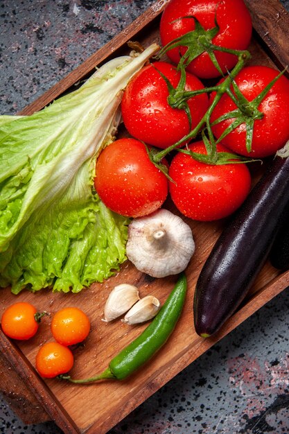 vista de cima legumes frescos tomates vermelhos alho salada verde e berinjelas dentro de tábua de madeira na superfície azul salada refeição comida cor madura almoço