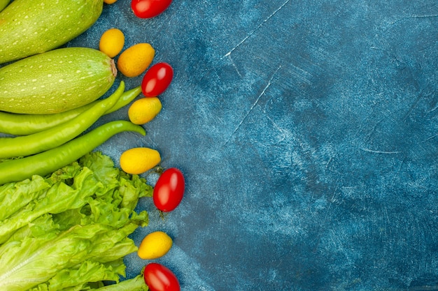 Foto grátis vista de cima legumes tomates cereja zacchini cumcuat pimenta verde alface na mesa azul