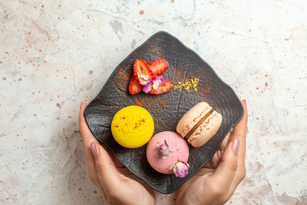 Vista de cima macarons franceses dentro do prato no bolo doce de biscoito de mesa branca