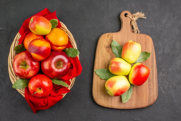 Vista de cima maçãs frescas com pêssegos dentro da cesta na mesa escura árvore de frutas frescas maduras