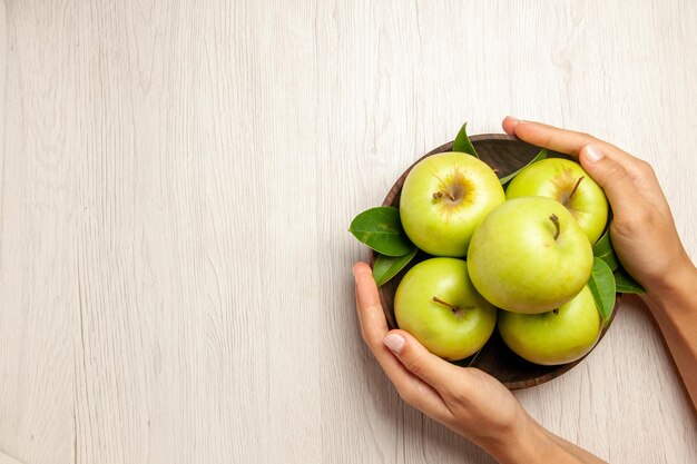Vista de cima maçãs verdes frescas frutas maduras e maduras na mesa branca planta frutas coloridas árvore verde fresca