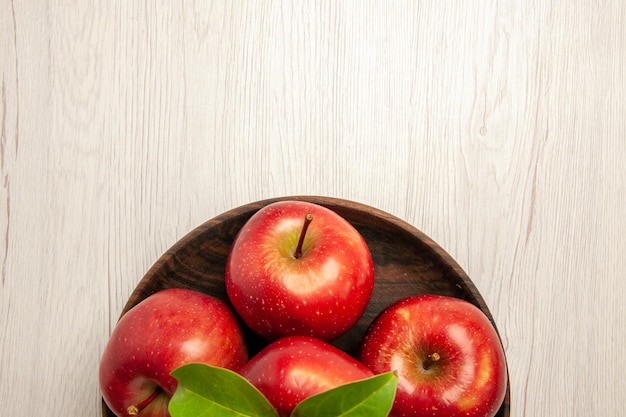 Vista de cima maçãs vermelhas frescas frutas maduras e maduras na mesa branca cor de frutas árvore planta fresca vermelha