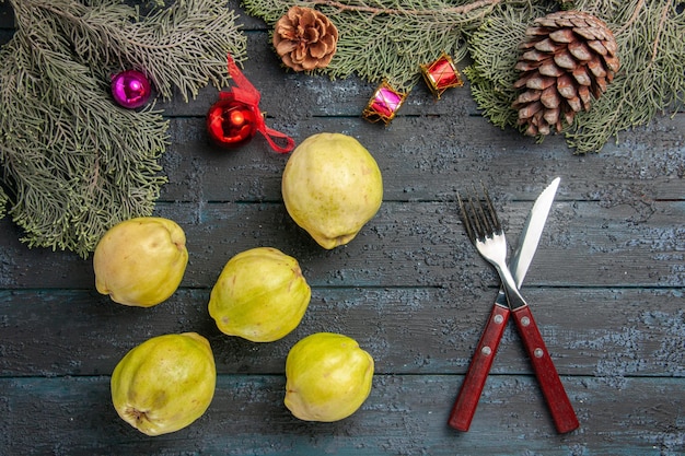 Vista de cima marmelos maduros frutas frescas em mesa rústica azul escura muitas plantas frescas árvore de frutas maduras