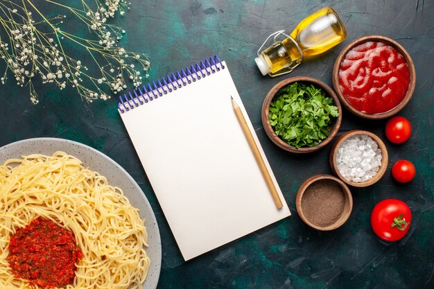 Foto grátis vista de cima massa italiana cozida com carne e temperos diferentes na superfície azul escura