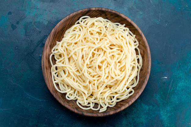 Vista de cima massa italiana cozida dentro de placa de madeira redonda sobre fundo azul macarrão itália comida jantar massa carne