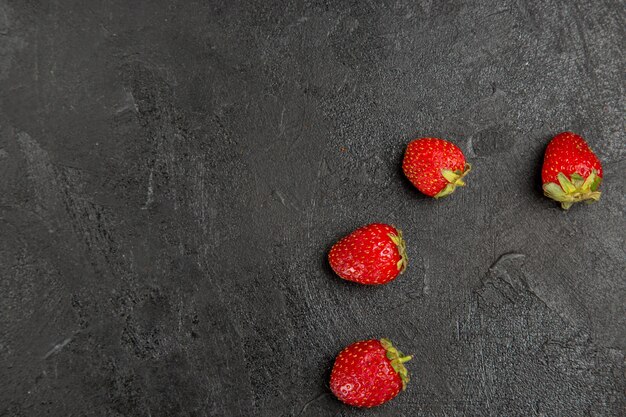 Vista de cima, morangos vermelhos frescos alinhados na mesa de cor escura, frutas vermelhas maduras