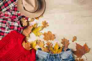 Foto grátis vista de cima na postura plana de estilo feminino e acessórios, suéter de malha vermelho, camisa de flanela quadriculada, jeans, chapéu, tendência da moda outono, vista de cima, roupas, folhas amarelas