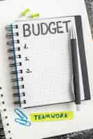 Foto grátis vista de cima orçamento escrito nota no bloco de notas com caneta na superfície escura caderno cor do aluno dinheiro cinza faculdade negócios
