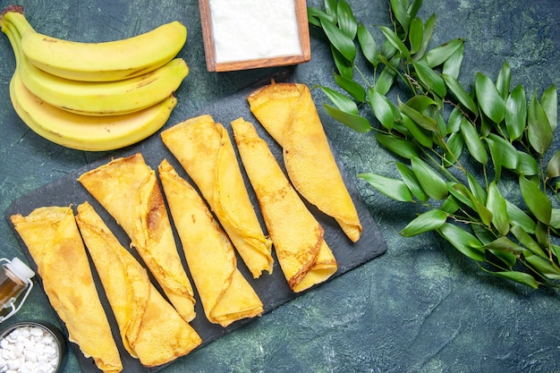 Vista de cima panquecas deliciosas com bananas em fundo escuro