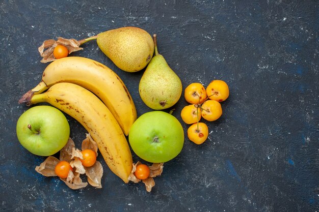 Vista de cima, par de bananas amarelas de frutas vermelhas com maçãs verdes, peras na mesa azul-escuro frutas bagas frescas vitamina doce saudável