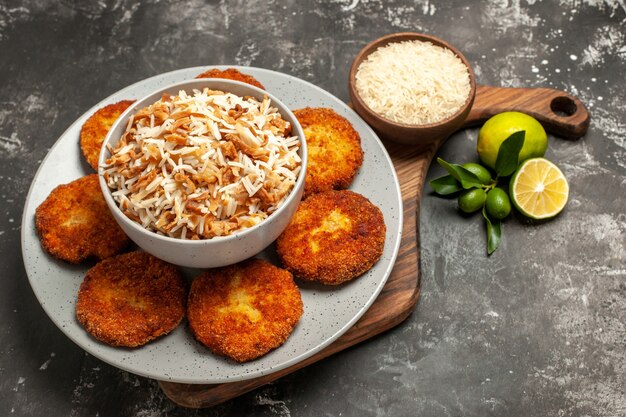 Vista de cima para baixo, saborosas costeletas fritas com arroz cozido em um prato de rissole de carne com superfície escura