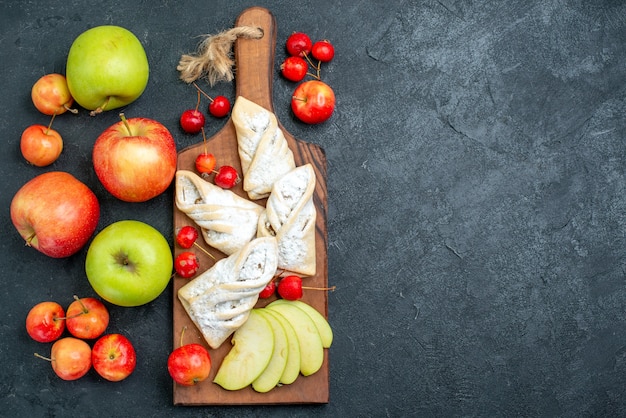 Vista de cima pastéis doces frutados com frutas frescas na superfície cinza-escuro torta de biscoito doce com açúcar