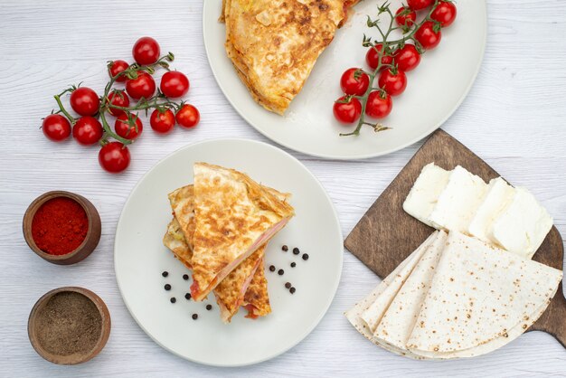 Vista de cima pastelaria com vegetais junto com temperos de queijo branco e tomates frescos na foto do almoço de refeição de comida de fundo branco