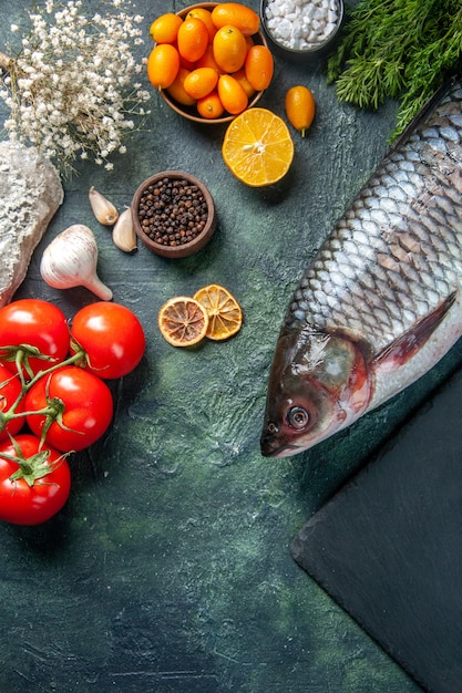 vista de cima peixe cru fresco com tomate e verduras em fundo escuro