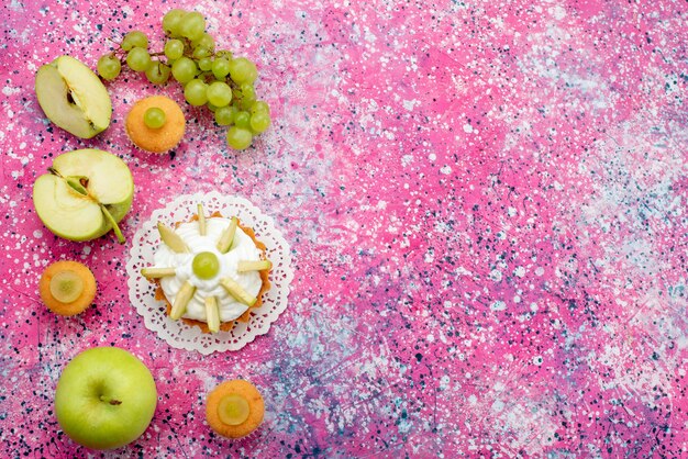 Vista de cima pequeno bolo delicioso com frutas fatiadas e creme no fundo colorido bolo doce cor de açúcar