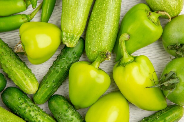 Vista de cima pimentos verdes frescos com pepinos verdes e tomates na mesa branca, salada madura, refeição quente