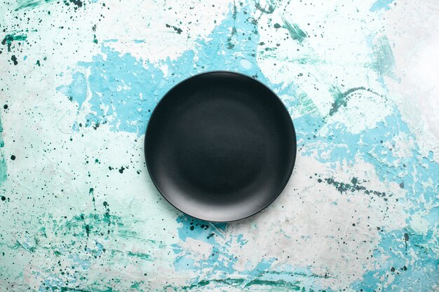 Vista de cima prato redondo vazio de cor escura no fundo azul prato de cozinha talheres de vidro