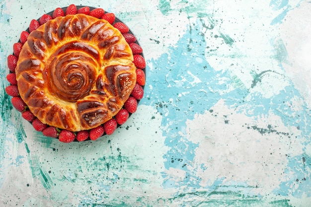 Vista de cima redonda deliciosa torta com morangos vermelhos frescos na superfície azul