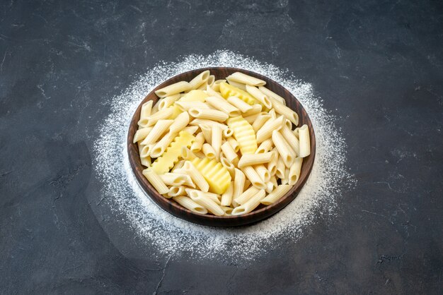 Vista de cima saborosa massa penne com batata em uma tigela polvilhada de farinha na mesa local de cópia