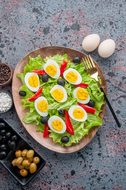 Vista de cima saborosa salada de ovo com salada verde e azeitonas em fundo claro