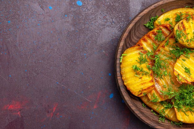 Vista de cima saborosas batatas cozidas com verduras dentro do prato na superfície escura cozinhando batatas fritas jantar