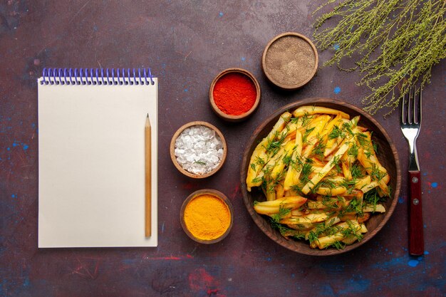 Vista de cima saborosas batatas fritas com verduras e temperos diferentes na superfície escura