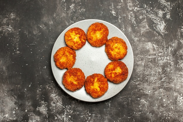 Vista de cima saborosas costeletas fritas dentro do prato em um prato de rissole de carne com superfície escura