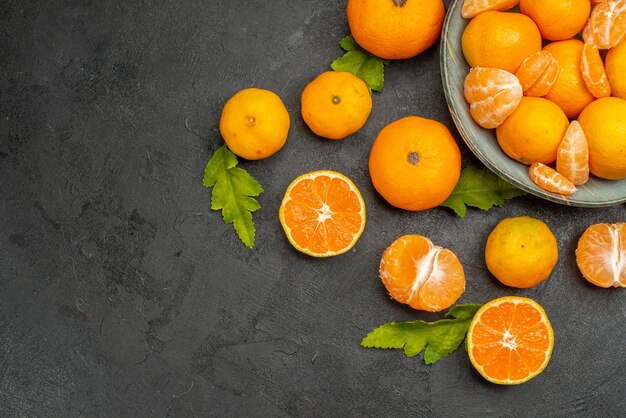 Vista de cima saborosas tangerinas suculentas dentro do prato em fundo escuro