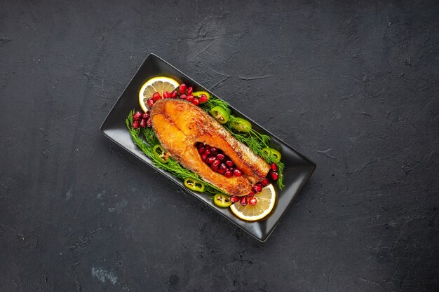 Vista de cima saboroso peixe cozido com verduras e romãs dentro da panela na mesa escura