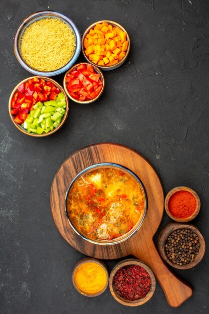 Vista de cima sopa saborosa com temperos diferentes e pimenta fatiada em fundo cinza refeição de sopa comida tempero de carne picante