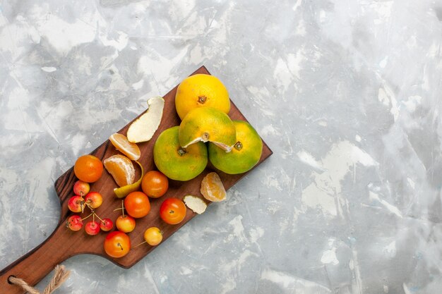 Foto grátis vista de cima tangerinas verdes frescas com cítricos maduros e azedos na mesa branca.