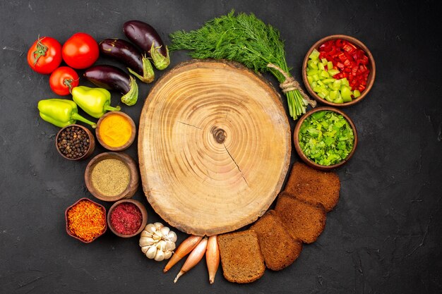 Vista de cima temperos diferentes com vegetais verdes e pães escuros no fundo escuro temperos para salada pão comida saudável