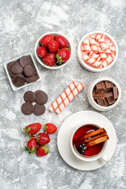 Vista de cima tigelas com chocolates de morango, doces e chá de sementes de anis de canela no fundo branco-acinzentado