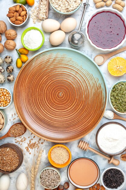 Vista de cima tigelas de prato redondo bege com grãos de trigo, sementes de gergelim, sementes de abóbora, nozes, ovos, cumcuats