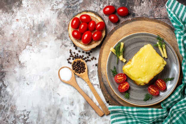 Vista de cima, tomate queijo e pão de queijo no prato na tábua de madeira tomates cereja na tábua de madeira colheres de madeira nua