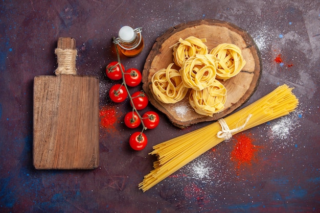 Vista de cima, tomates vermelhos frescos com massa italiana crua no fundo escuro Refeição de macarrão com salada crua